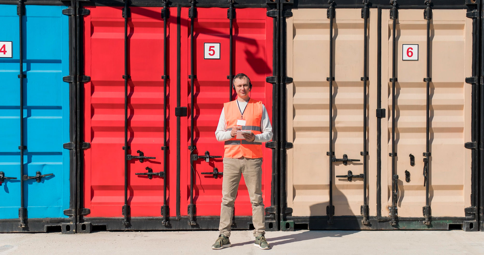 Internal communications in the transport and logistics sector showing a worker in front of shipping containers