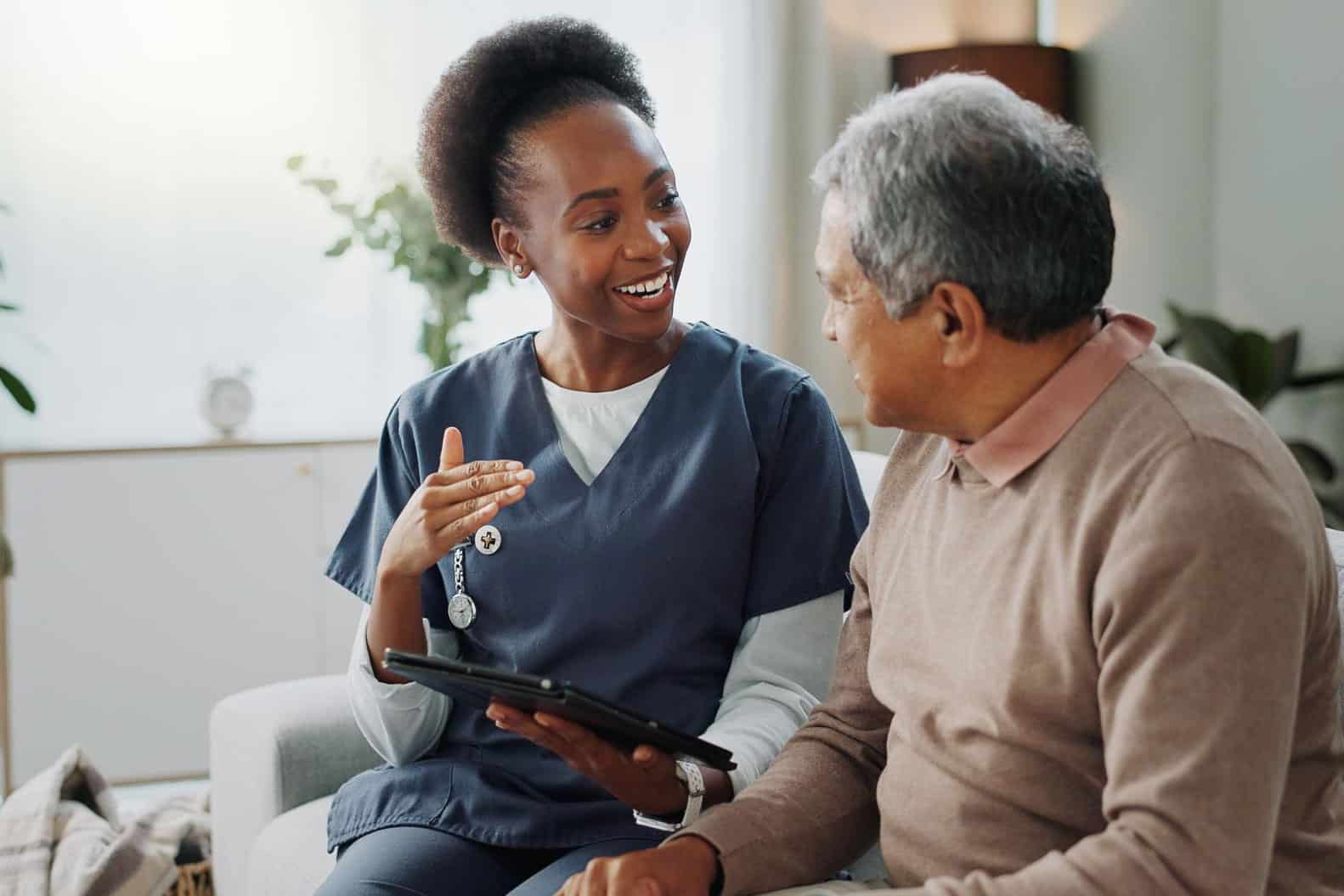 healthcare-internal-comms-deskless-workers-commskit young healthcare worker talking to an older patient in a deskless environment